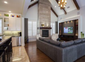 Modern living room with vaulted ceilings, faux wood shutters, and a cozy fireplace.